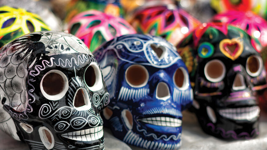 Ornately decorated ceramic skulls, symbols of the Day of the Dead tradition, are displayed in a row featuring vibrant patterns and intricate designs.