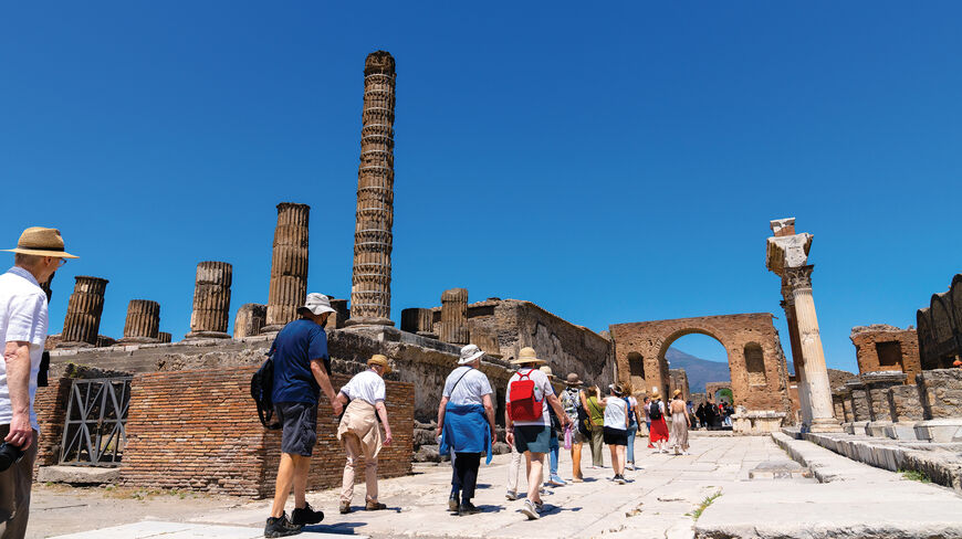 A group of tourists explores the ancient stone ruins and towering columns of Sorrento, Italy, while discovering the region’s rich history and mythology.