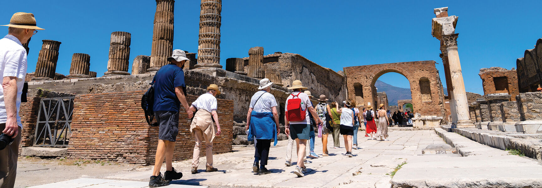 A group of tourists explores the ancient stone ruins and towering columns of Sorrento, Italy, while discovering the region’s rich history and mythology.