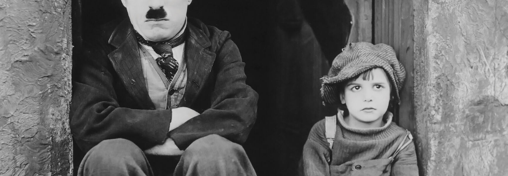 Charlie Chaplin and a young boy sit on a doorstep in a scene from a silent film comedy at Georgia’s Jekyll Island.