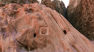 A rock carving of the face of T.E. Lawrence, also known as Lawrence of Arabia, on a red rock formation in Wadi Rum.