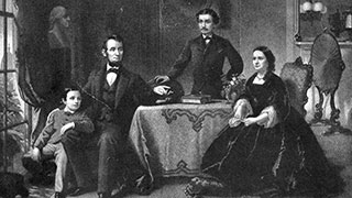 A black and white portrait of Abraham Lincoln with his wife, Mary Todd, and their sons, Robert and Tad, in a formal room.
