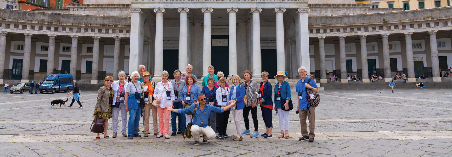 A group of travelers poses in Naples, Italy, in front of the San Francesco di Paola church in the Piazza del Plebiscito.