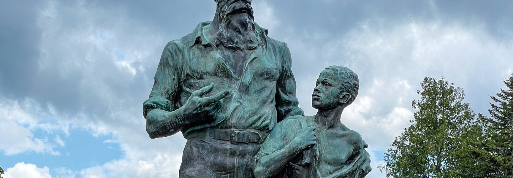 Bronze statue of John Brown and a young boy, representing 1850s America — Road to the Civil War, standing in an outdoor park.