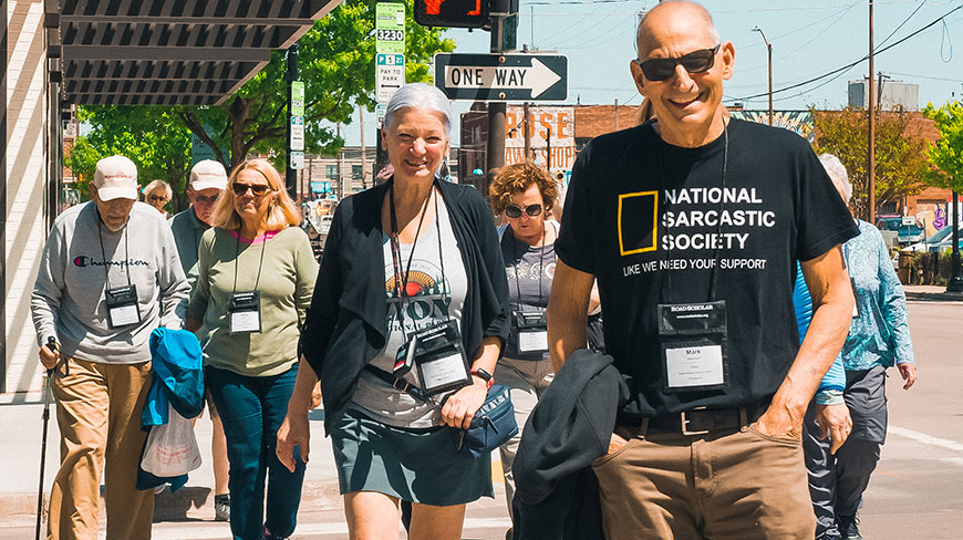 A group of seniors participates in a walking tour along a sunny city sidewalk in Salt Lake City, Utah.