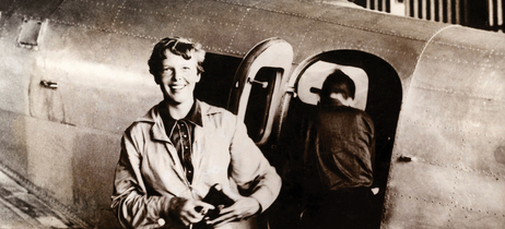 Amelia Earhart smiles while standing in front of her Lockheed Electra airplane during her 1937 attempt to fly around the world.