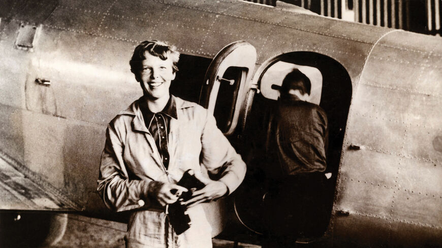 Amelia Earhart smiles while standing in front of her Lockheed Electra airplane during her 1937 attempt to fly around the world.