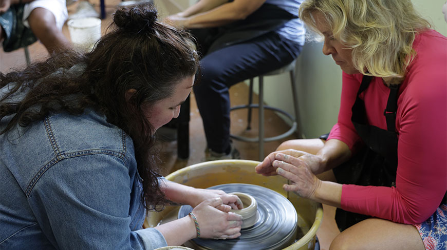 Two women work together on a pottery wheel at Squire Studio in New York.
