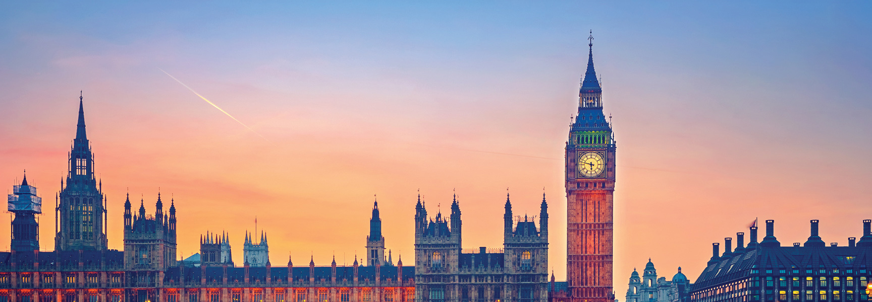 The Houses of Parliament and Big Ben clock tower in London are shown at sunset against a colorful sky.