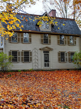 The historic Old Manse in Concord surrounded by vibrant autumn foliage and fallen leaves as part of a Literary New England tour.