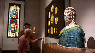 Visitors view art exhibits, including a colorful ceramic bust and stained glass, inside the Getty Museum in Los Angeles.