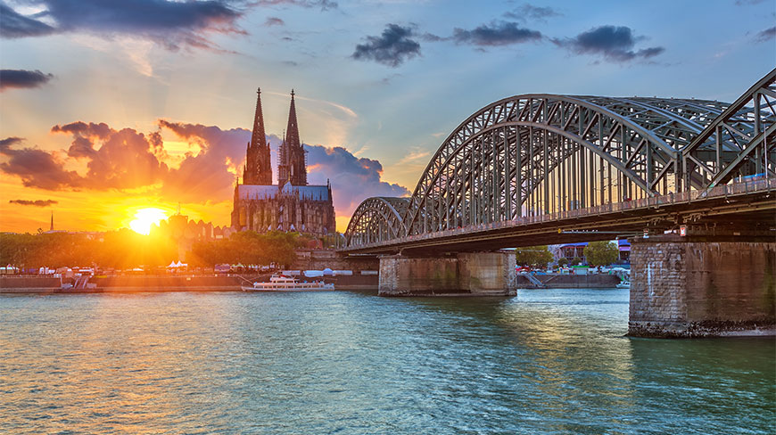 Sunset over the Rhine River with the Cologne Cathedral and bridge in Cologne, Germany.