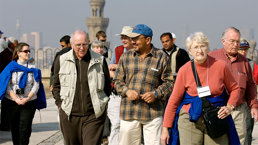 EG participants walking outdoors with an Egyptian cityscape and a minaret in the background.