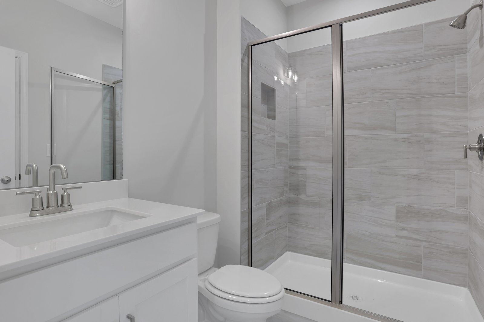 secondary bathroom with white cabinets and tile flooring