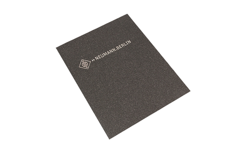 Neumann.Berlin Merchandise. Silbernes Logo auf grauem Notizbuch