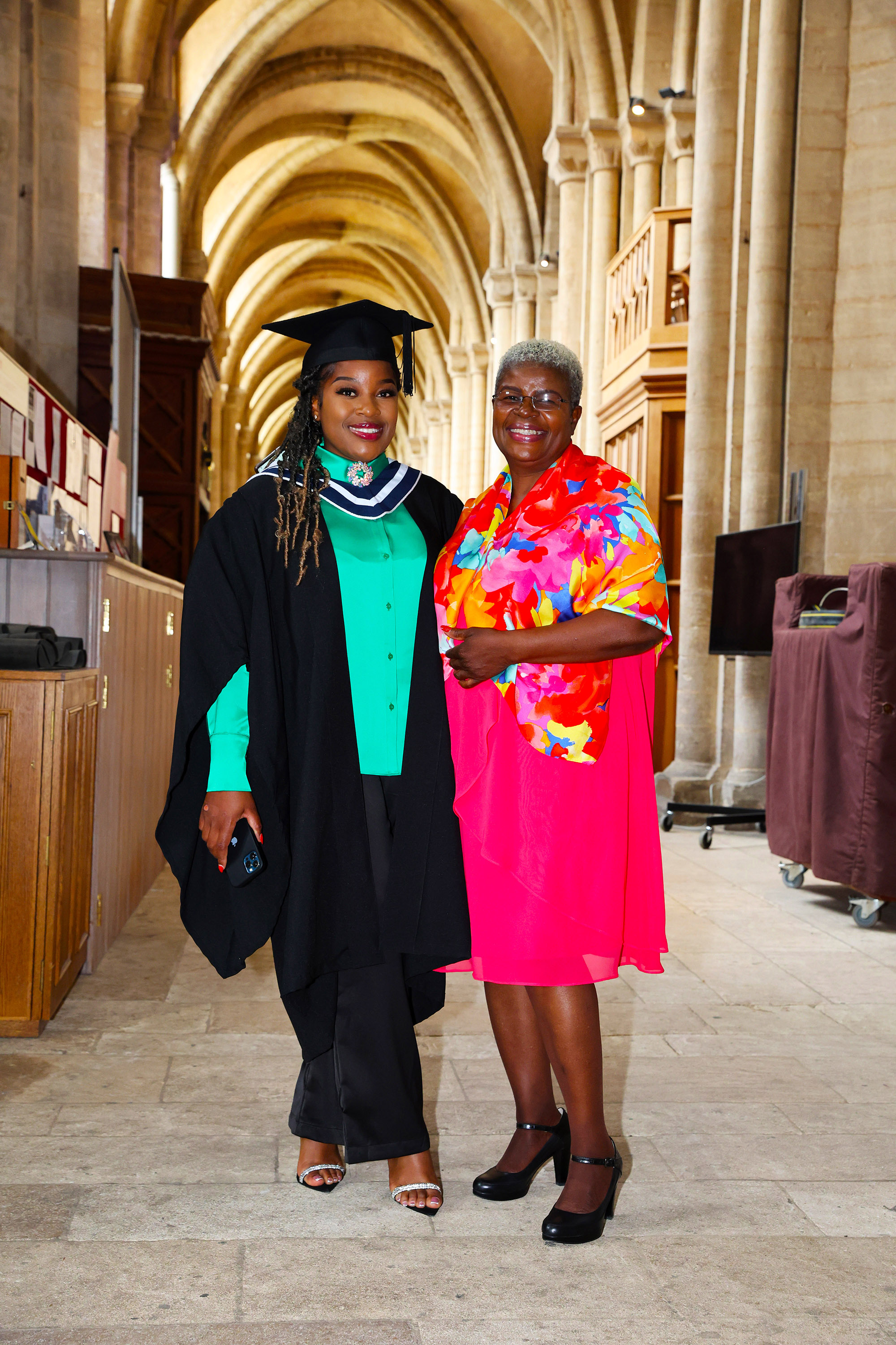 A graduate and a woman posing together in a church hallway