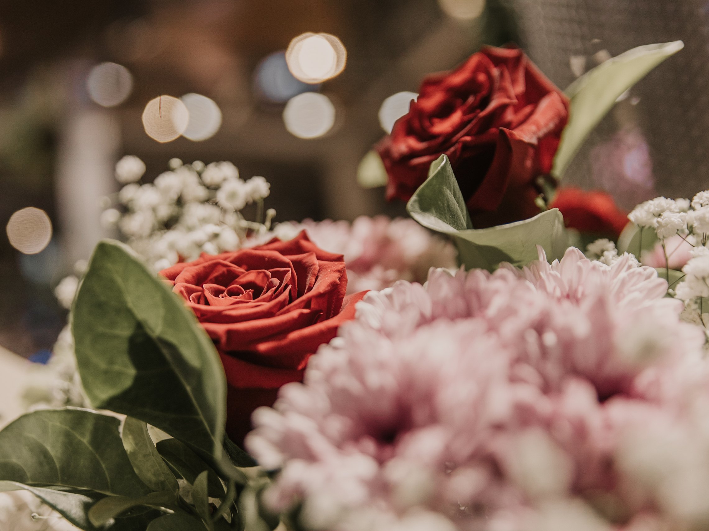 A bouquet of mixed flowers featuring two red roses, arranged for Valentine's Day.