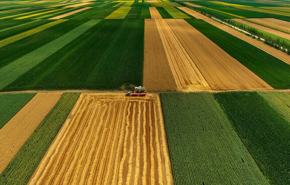 Aerial view of crops being harvested from fields 