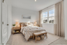 secondary bedroom with bed, nightstands, and curtains around large windows