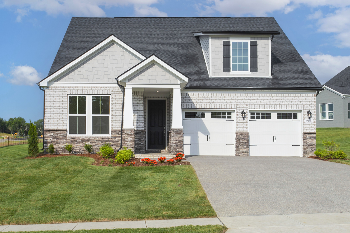 exterior with brick, stone, and two car garage
