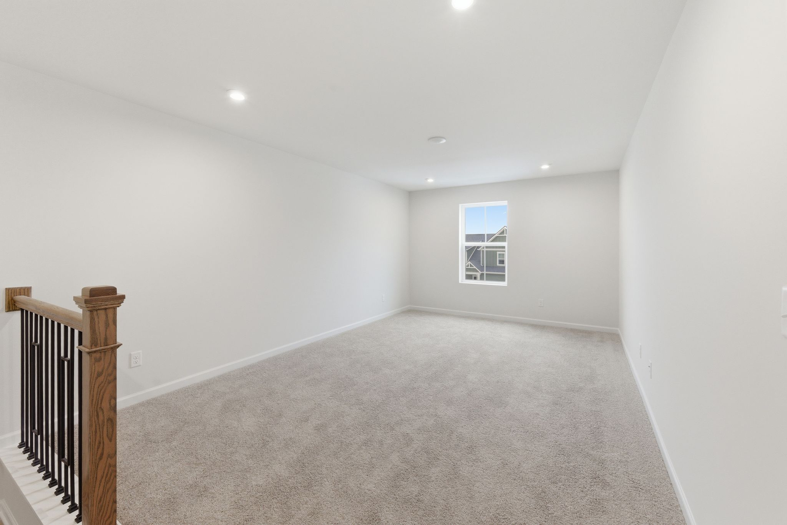 loft space with carpet flooring, white trim, and a view of the staircase