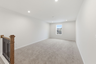 loft space with carpet flooring, white trim, and a view of the staircase