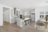 open-concept kitchen with quartz countertops, black barstools, and stainless-steel appliances