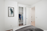 spacious bed with grey bedsheets, a closet with a sliding door, and framed artwork