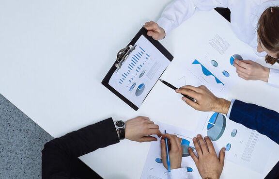 Top down view of three business professionals looking at charts and graphs