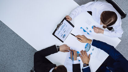 Top down view of three business professionals looking at charts and graphs