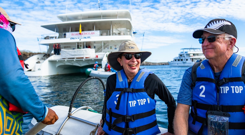 Road Scholars smile in a small boat floating among other boats off the coast