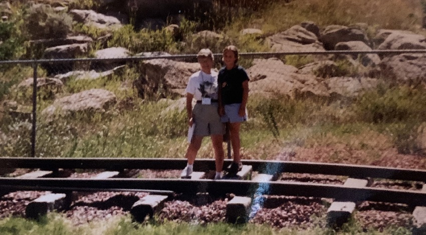 Beckah and her grandmother stand on train tracks with rocks in the background