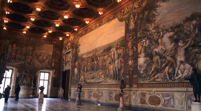 Large paintings cover the walls of a museum, with statues lining the walls