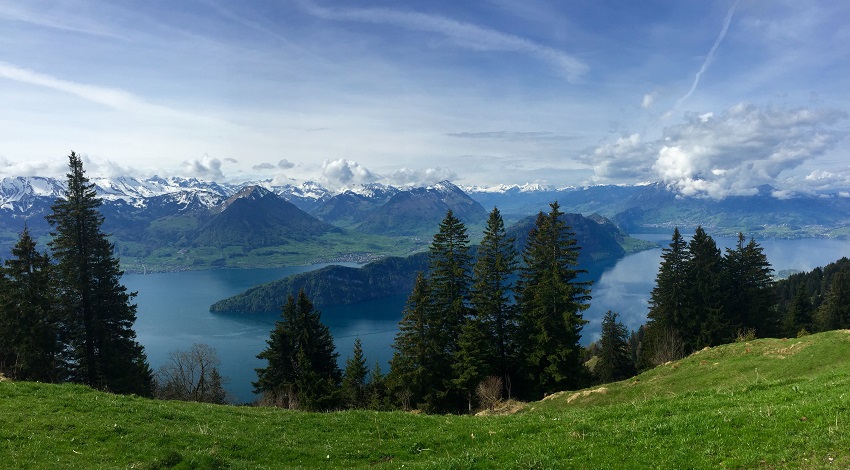 A panoramic view of Swiss meadows, lakes and mountains