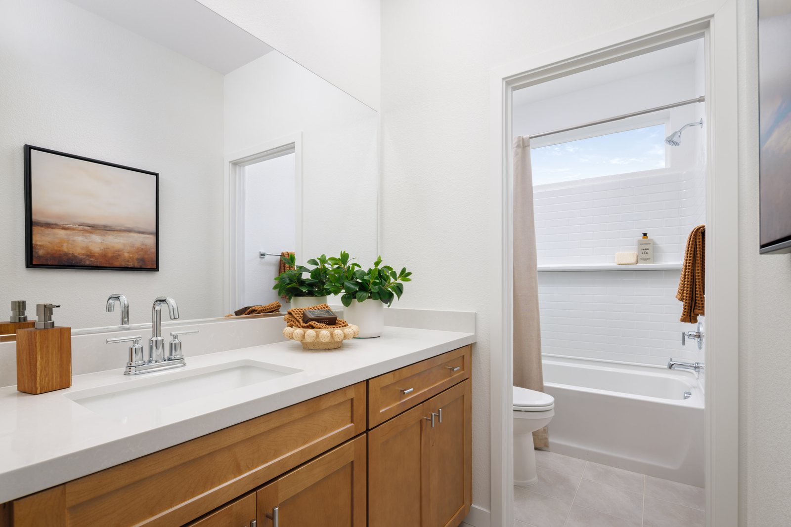 bathroom with light wood cabinets, white counter, and tub with shower overhead