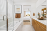 bathroom with light wood cabinets, white counters, two sinks, tub, and shower