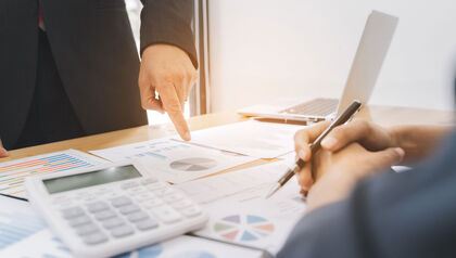Desk covered in financial paper work and calculator