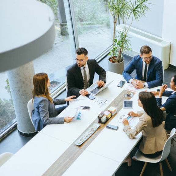 Overhead view of 5 men and women sitting at conference table