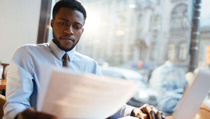 Business man reviewing paperwork in front of a laptop