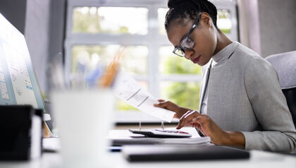 Woman sitting at a desk with computer, papers and calculator