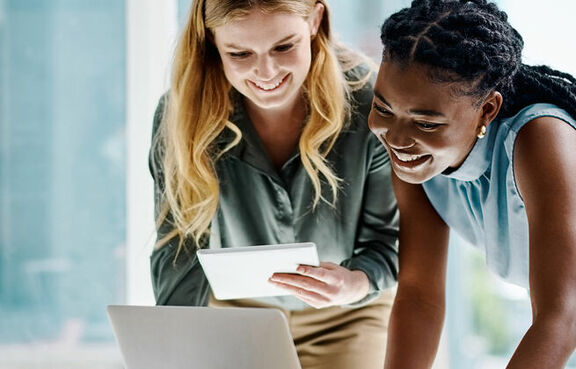 Two woman looking at a laptop on a desk 