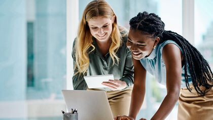 Two woman looking at a laptop on a desk 