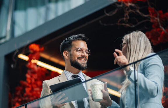 Professionally dressed man and woman talking outside an office building