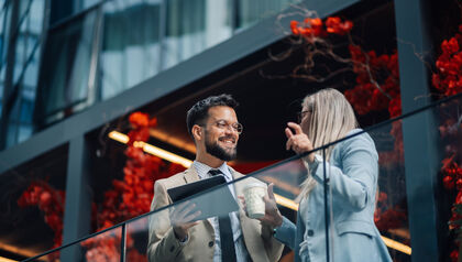 Professionally dressed man and woman talking outside an office building