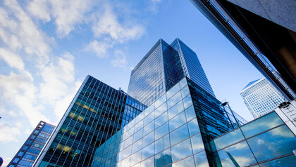 Tall glass-covered buildings against a cloudy blue sky 