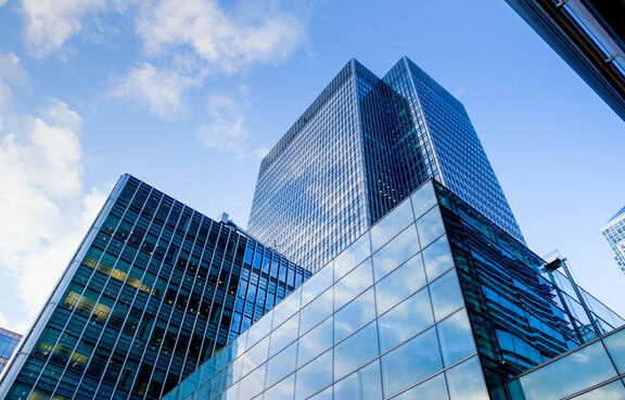 Tall glass-covered buildings against a cloudy blue sky 