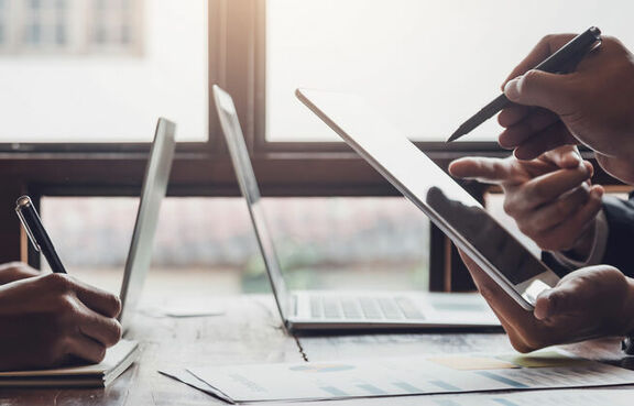 Business people sitting at a meeting table in front of laptops 