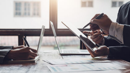 Business people sitting at a meeting table in front of laptops 