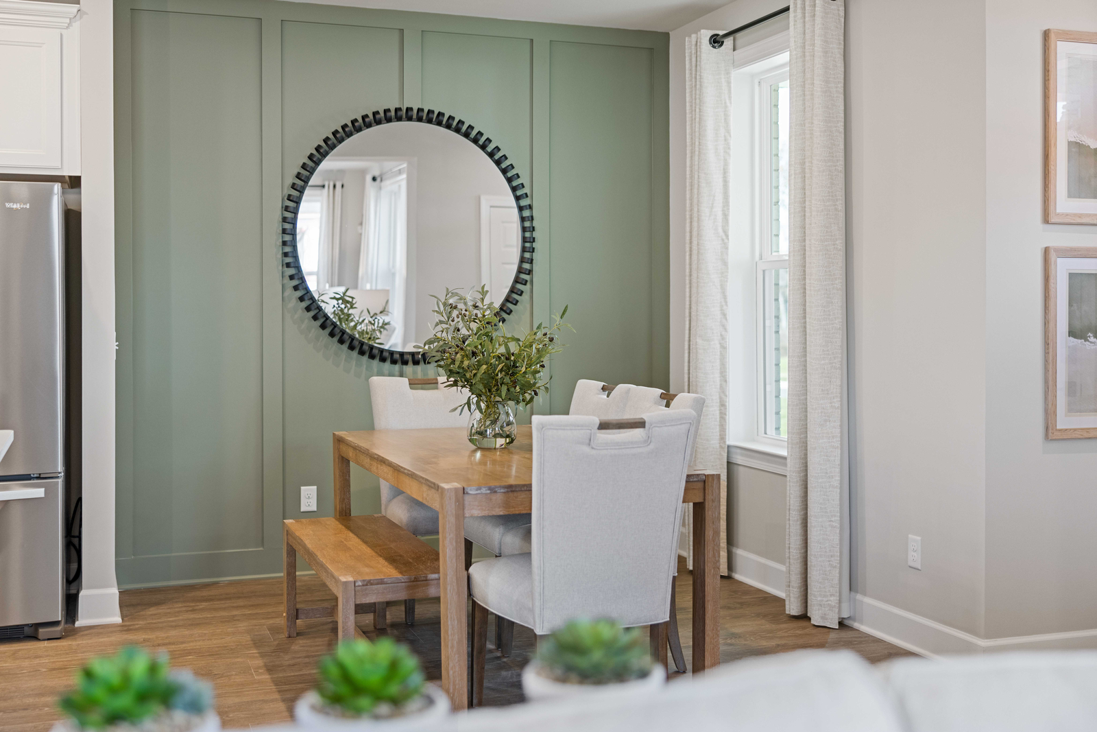 dining room with wood flooring, green accent wall, dining room table with chairs, and a window