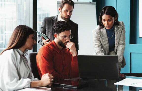 Businesspeople collaborating around laptop in an office